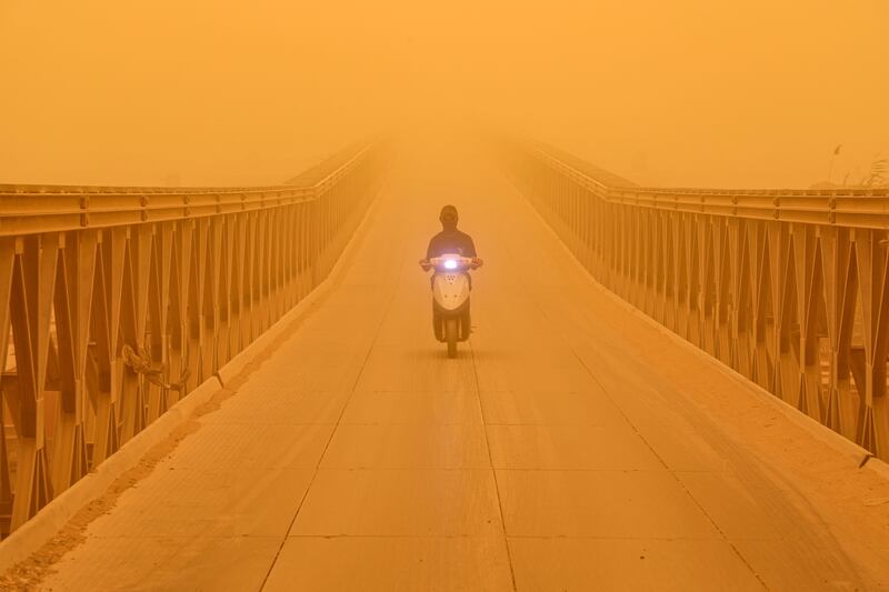 A motorist drives a scooter along a bridge in the city of Nasiriyah, Iraq, during a heavy dust storm. AFP