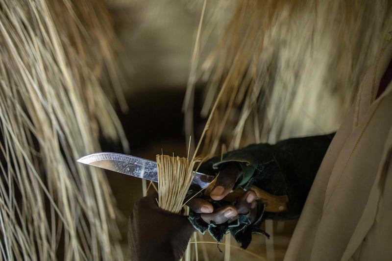 An artisan cuts thatching to be used in the reconstructed Kasubi Royal Tombs building.