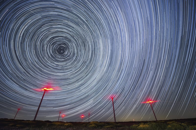 A rendered timelapse image shows circumpolar stars over some windmills taken from La Lora wasteland in Cantabria, Spain, early 31 May 2022.   EPA / Pedro Puente Hoyos