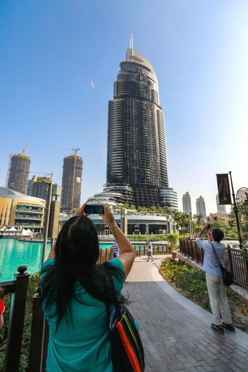A woman takes a photo of the damaged hotel in Downtown Dubai.