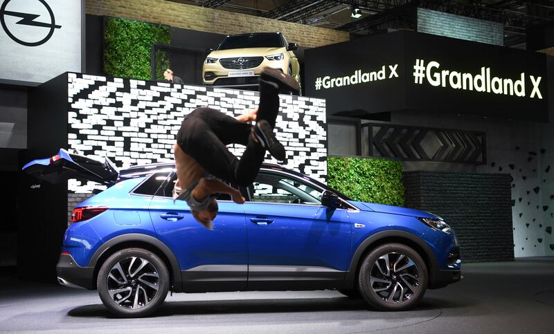 A parkour runner jumps for joy in front of the Opel Grandland X cross-over. Arne Dedert / dpa via AP