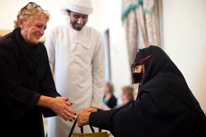 Al Rams, Ras Al Khaimah, United Arab Emirates - July 17 2013 - An expat hands a thank you gift to Fatima Bishr (70) after Fatima cooked an Iftar. Expats attended their first Iftar at Fatima Bisher's home in Al Rams, Ras Al Khaimah. The event was hosted by the Al Qasimi Foundation, which is based in RAK. For story by Rym Ghazal.  (Razan Alzayani / The National)  *** Local Caption ***  RA0718_expat_iftar_RAK025.jpg
