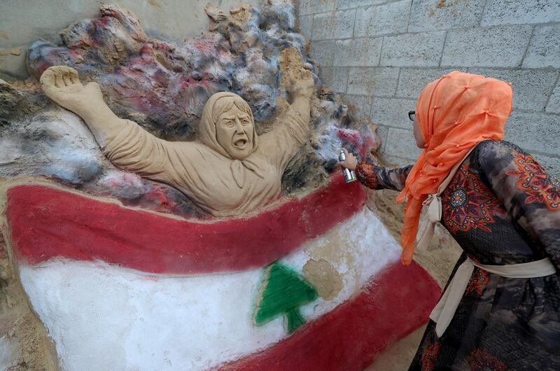 A Palestinian artist paints the colours of the Lebanese flag on a sand sculpture to show solidarity with the Lebanese people following Beirut's massive blast, in Gaza City. Reuters