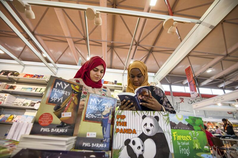 SHARJAH, UNITED ARAB EMIRATES - These women are so engrossed with the books they are reading at The Sharjah Book Fair.  Leslie Pableo for The National