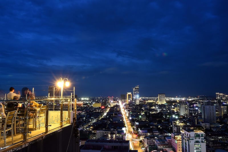 This picture taken on July 30, 2018 shoes a general view of the city skyline at dusk in Phnom Penh. / AFP PHOTO / MANAN VATSYAYANA