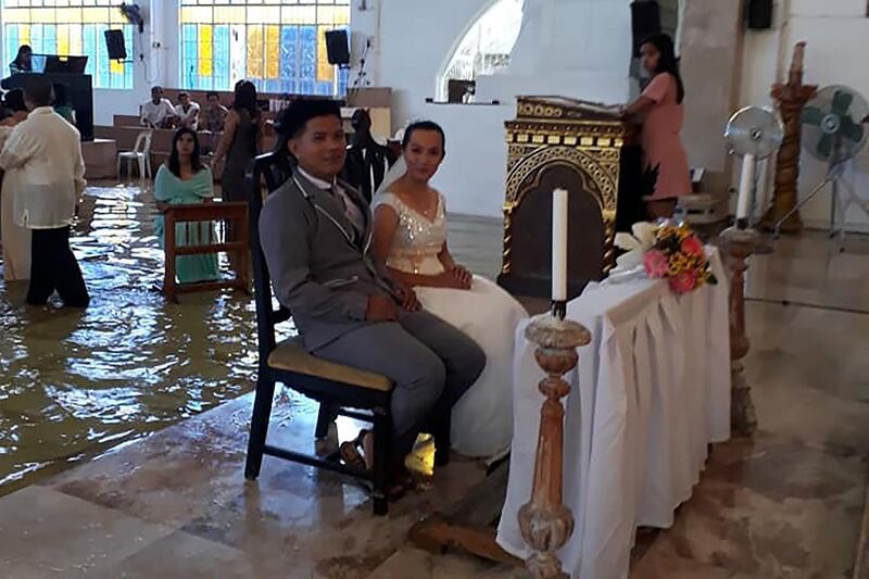 This handout photo taken from the facebook of Bautista Banares Tere on August 11, 2018 shows the bride Jobel Delos Angeles, 24, and her groom during their wedding amidst a flooded church in Hagonoy town, Bulacan town, north of Manila on August 11, 2018. - A beaming bride defiantly marching up a flooded church aisle in the Philippines has won hearts as the country suffers a fresh bout of monsoonal rains. (Photo by Bautista Banares Tere / Bautista Banares Tere / AFP) / --EDITORS NOTE -- RESTRICTED TO EDITORIAL USE MANDATORY CREDIT " AFP PHOTO / Bautista Banares Tere" NO MARKETING NO ADVERTISING CAMPAIGNS - DISTRIBUTED AS A SERVICE TO CLIENTS - NO ARCHIVES