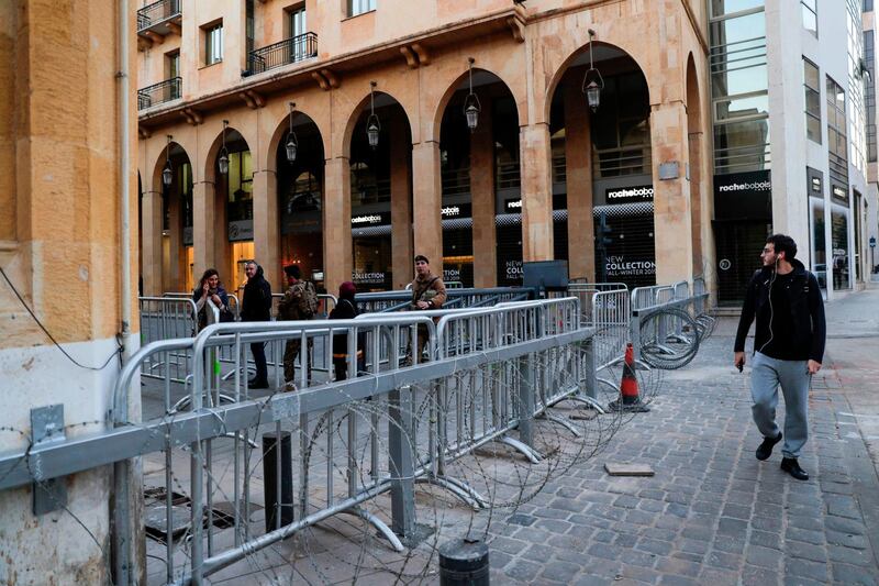 People walk past a metal barrier on a road leading to the Lebanese Parliament in the capital Beirut on December 18, 2019. Lebanon increased security around protest centres in central Beirut after several nights of violence last week disrupted two months of largely peaceful anti-government demonstrations. An officer who spoke to AFP on condition of anonymity said the barriers were intended to protect demonstrators from attacks. / AFP / ANWAR AMRO
