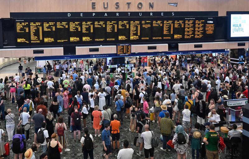 Rail passengers look at departures boards as they wait to board trains at Euston Station in London on Sunday. AFP