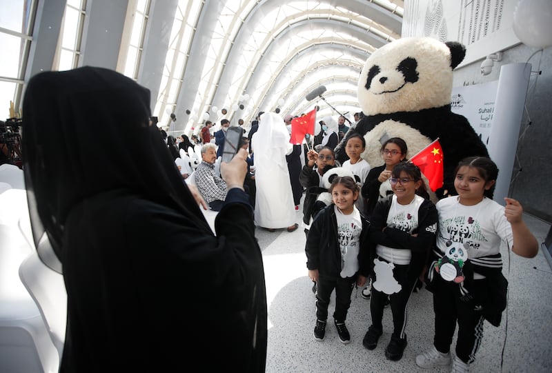 Children pose for a photograph in front of a giant panda teddy on the day two pandas arrived from China. Reuters