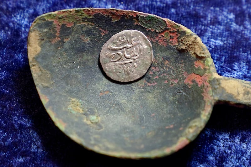 A 17th century Arabian silver coin that research shows was struck in 1693 in Yemen, rests in a 17th century brass spoon on a table, in Warwick, R.I., Thursday, March 11, 2021. The coin was found at a farm, in Middletown, R.I., in 2014 by metal detectorist Jim Bailey, who contends it was plundered in 1695 by English pirate Henry Every from Muslim pilgrims sailing home to India after a pilgrimage to Mecca. (AP Photo/Steven Senne)