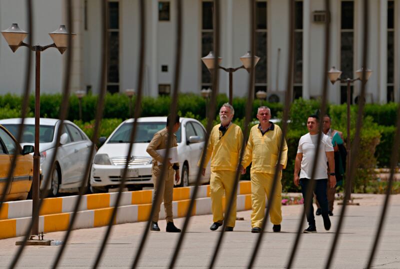 Jim Fitton, center left, and Volker Waldmann, center right, are handcuffed as they walk outside a courtroom in Baghdad, Iraq. AP.