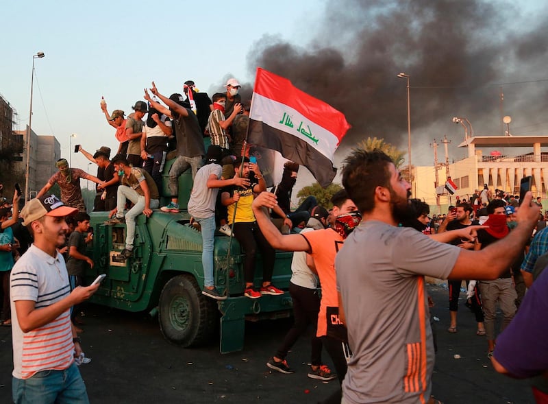 Anti-government protesters take over an armoured vehicle before they burn it in Baghdad.  AP Photo