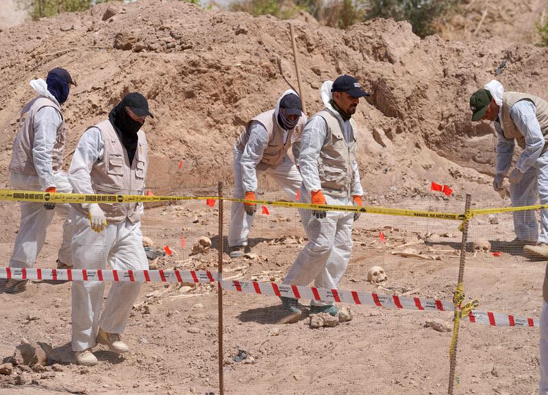 Forensic experts exhume and number human remains found in a mass grave near Najaf.