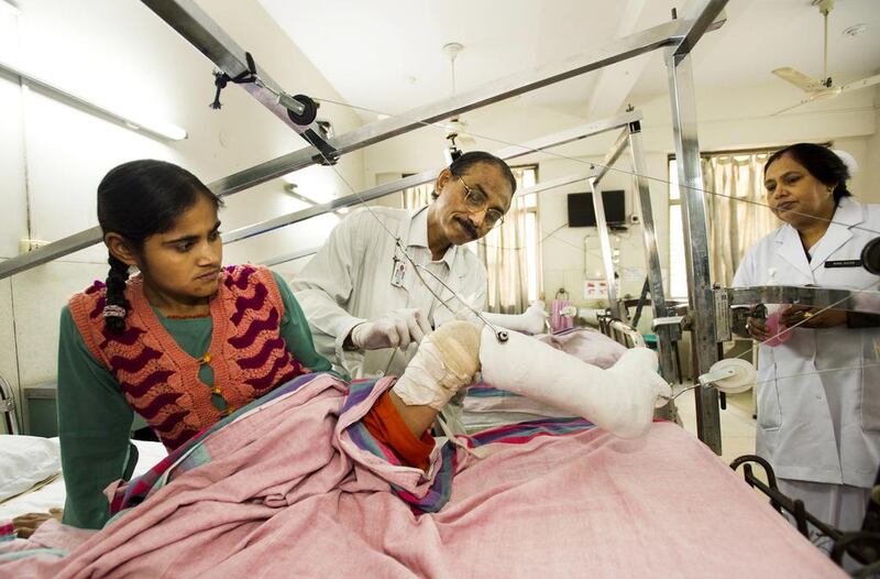 Dr Mathew Varghese examines a patient in India's only polio ward at St Stephen's Hospital in New Delhi, where deformities caused by the disease can be corrected with surgery and patients are fitted with prosthetics to increase their mobility. Simon de Trey-White for The National