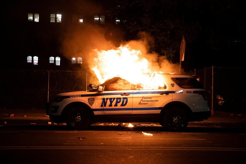 A NYPD police car is set on fire as protesters clash with police during a march against the death in Minneapolis police custody of George Floyd, in the Brooklyn borough of New York City, U.S., May 30, 2020. Picture taken May 30, 2020. REUTERS/Jeenah Moon     TPX IMAGES OF THE DAY