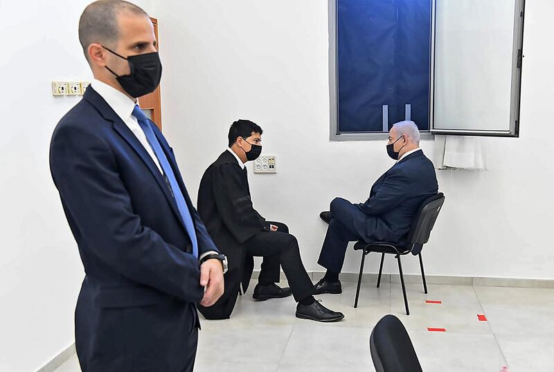 Israeli Prime Minister Benjamin Netanyahu, seated right, discusses his trial for corruption with his lawyer before a hearing begins at Jerusalem District Court. Mr Netanyahu, who denies the charges, also has a fourth national election in two years to contend with. AFP