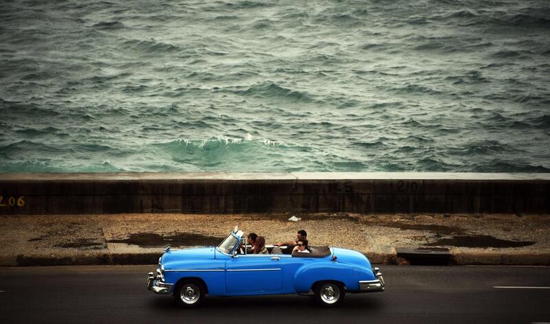 People ride a US-made vintage car along the Malecon in Havana. Rodrigo Arangua / AFP Photo