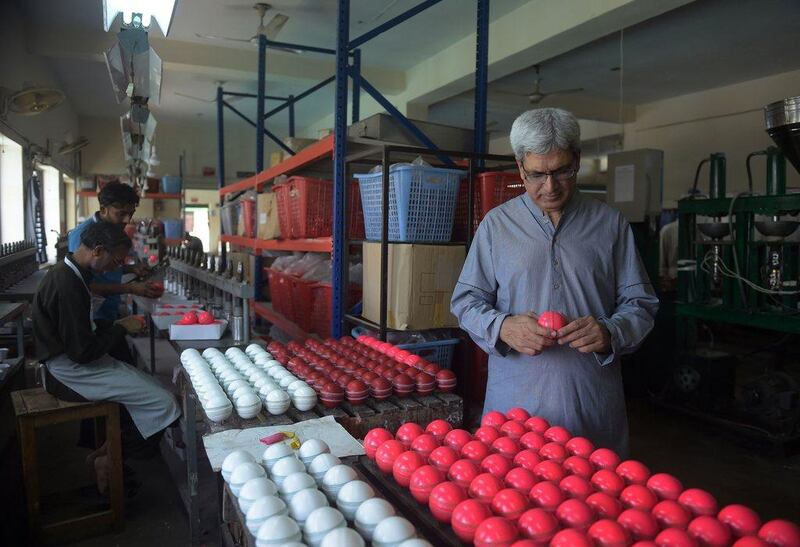 In this photograph taken on May 27, 2016, Chief Executive of ‘Grays of Cambridge’, Khawar Anwar Khawaja inspects a pink cricket ball at the factory in Sialkot. Pakistan’s sports goods industry is positioning itself to be the prime manufacturer of pink cricket balls — a high-visibility alternative for use in day-night Test matches aimed at dragging the game into the 21st century. Aamir Qureshi / AFP