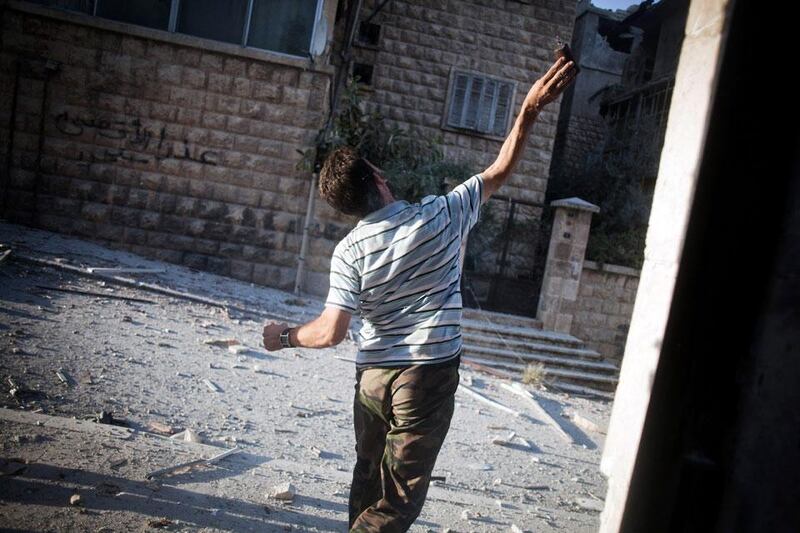 A Free Syrian Army (FSA) solider throws a home-made grenade towards a Syrian Army position in the Izaa district.  Manu Brabo / AP Photo