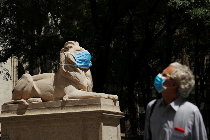 A large mask hangs on the face of a lion statue standing outside of the main branch of the New York Public Library in the Manhattan borough of New York City, US. Reuters