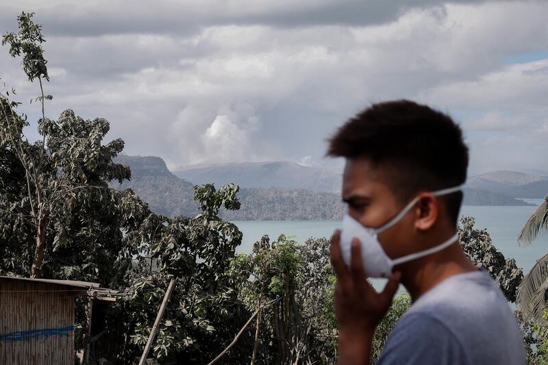 A man wears a mask as the Taal volcano continues to spew smoke and ash in Tanuan, Batangas, Philippines. EPA