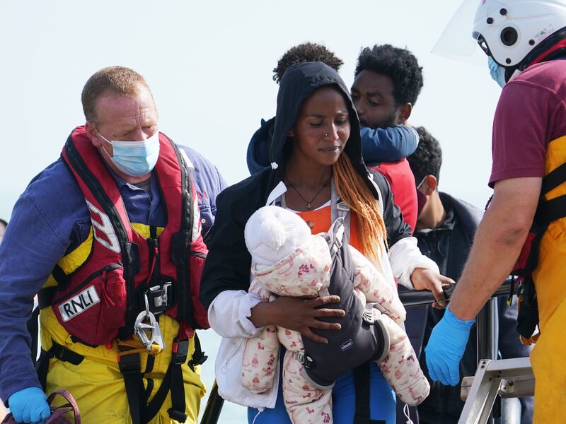 A woman cradles a baby as she and fellow migrants are brought ashore from a lifeboat at Dungeness in Kent. Getty Images