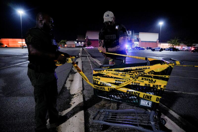 Officers attach a crime scene tape to a shopping cart at the mall. Reuters
