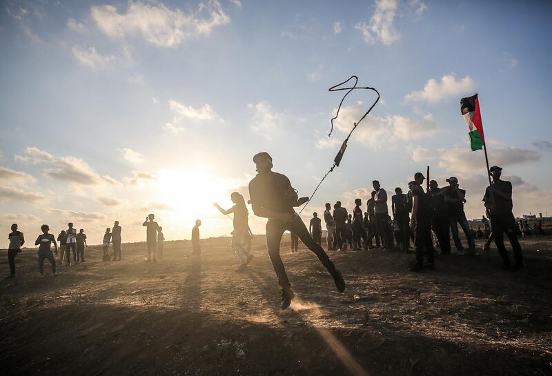 Palestinian protesters throw stones with slingshots during clashes near the border between Israel and eastern Gaza Strip.  EPA