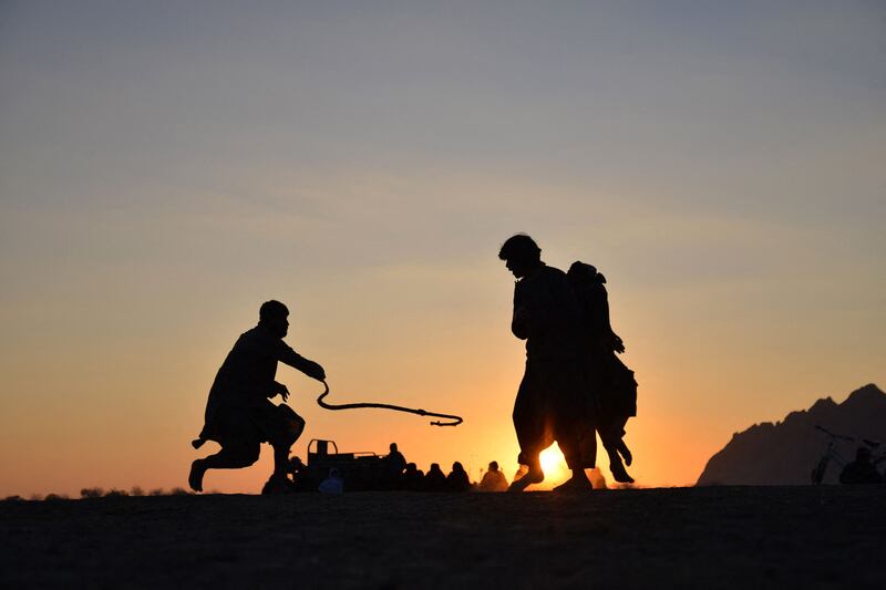 Afghan men play a traditional rope game 'Dora' along a field in Dand district of Kandahar province. AFP