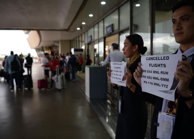 Airline staff hold placards announcing the cancellation of flights at terminal one of the Manila international airport hours before the deadline of the closure of the airport due to Typhoon Kamurri. AFP