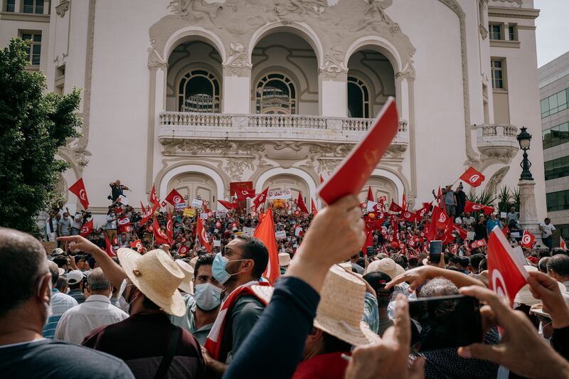 A woman holds up a copy of the 2014 constitution in front of a large crowd on the steps of the national theatre in downtown Tunis on Sunday.