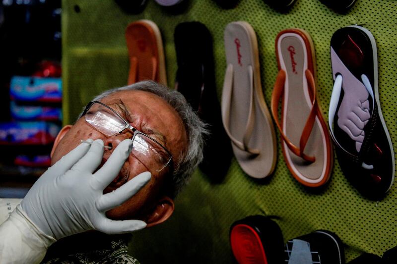 A vendor reacts as a healthcare worker in protective gear collects a swab sample to be tested for the coronavirus at a traditional market in Jakarta, Indonesia. Reuters