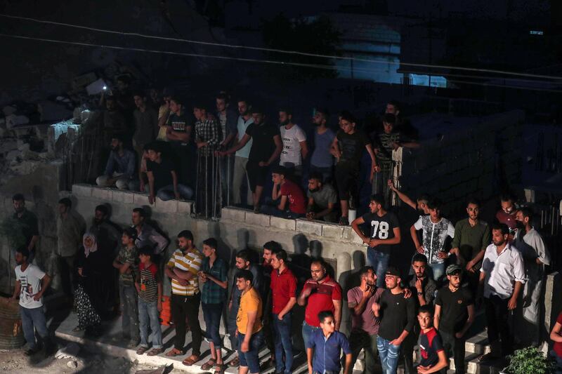 People watch as members of the Syrian Civil Defence, also known as the "White Helmets", attempt to clear debris as they search for bodies or survivors in a collapsed building following a reported government air strike in the village of Saraqib in Syria's northwestern Idlib province.  AFP