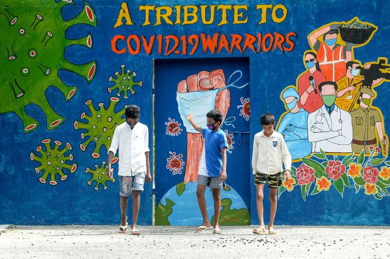 A youth gestures as he walks with others past a mural dedicated to frontline workers in Chennai. AFP
