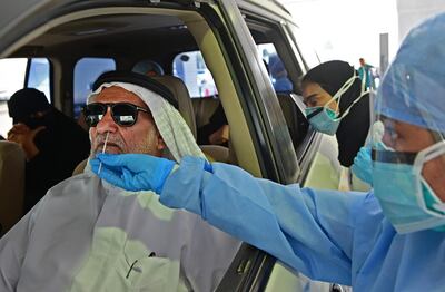 A nurse uses a swab to test the passenger of a car for COVID-19, at a drive thru verification centre in the Emirati capital Abu Dhabi on April 2, 2020.  / AFP / GIUSEPPE CACACE
