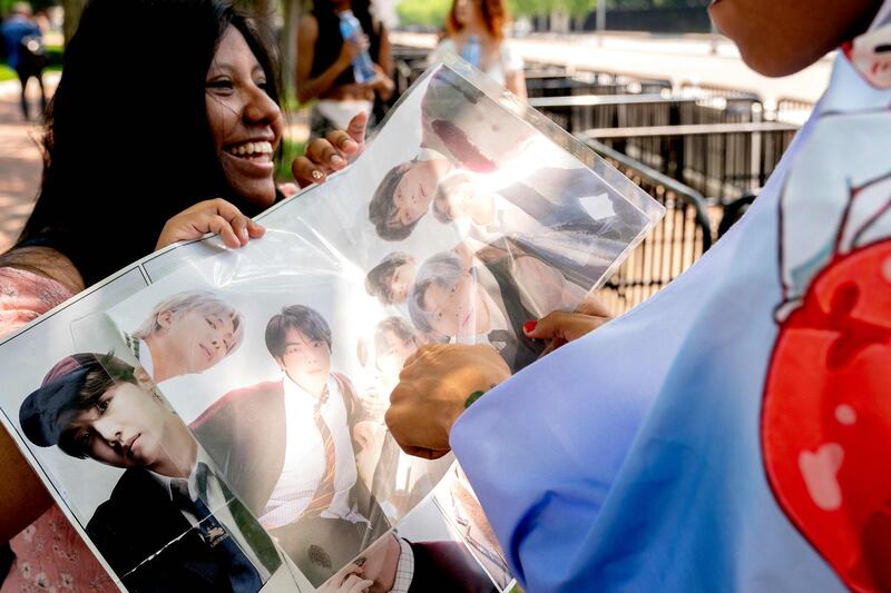 A fan of BTS holds up a poster of the band outside the White House. AFP
