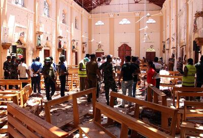 TOPSHOT - Sri Lankan security personnel walk through debris following an explosion in St Sebastian's Church in Negombo, north of the capital Colombo, on April 21, 2019. A series of eight devastating bomb blasts ripped through high-end hotels and churches holding Easter services in Sri Lanka on April 21, killing nearly 160 people, including dozens of foreigners. / AFP / STR
