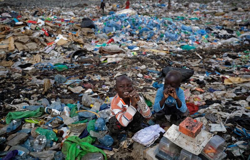 Two young boys build a small tower from plastic containers in the trash, while their parents work to scavenge recyclable materials, at the dump in the Dandora slum of Nairobi, Kenya. AP Photo