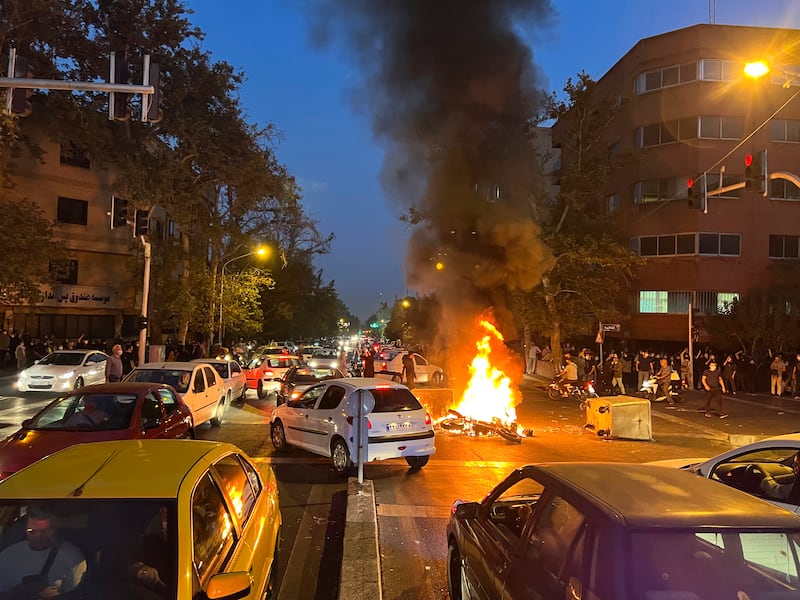 A police motorcycle burns during a protest over the death of a young woman who had been detained for violating the country's conservative dress code, in downtown Tehran, Iran. AP