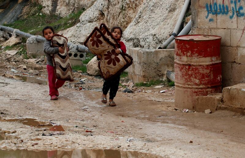 Internally displaced Syrian girls carry their belongings in an IDP camp located in Sarmada in Idlib province, Syria. REUTERS