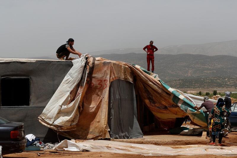 Syrian men remove cloth from their makeshift shelter, as they prepare to leave an informal refugee camp in Deir Al-Ahmar, east Lebanon. AP Photo