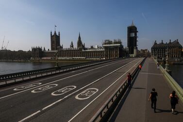 Pedestrians cross a quiet Westminster Bridge in view of the Houses of Parliament in London on April 9. Movement restrictions to prevent the spread of the coronavirus have been in place in the UK since March 23. Bloomberg