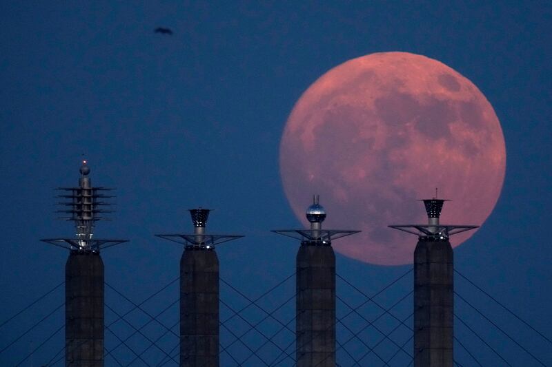 The waxing gibbous moon rises behind sculptures on top of support pylons at Bartle Hall convention centre in Kansas City, US. AP