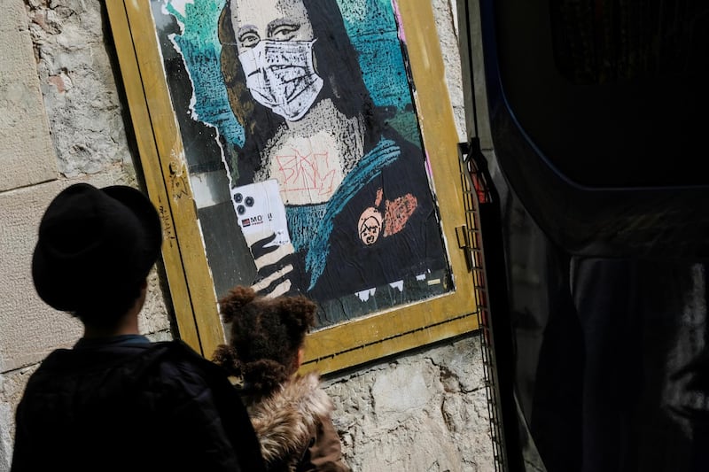 Children walk past an image of Mona Lisa with a protective face mask after further cases of coronavirus were confirmed in Barcelona, Spain. REUTERS