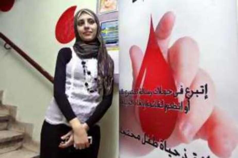 Shahinaz Mohammed, 24, stands besides a blood-drive banner at Ressella in Cairo, Egypt on October 9, 2008. She has been involved with the charity since 2000. Photo: Victoria Hazou for the National *** Local Caption ***  VH_ShahinazRessella.05.JPG