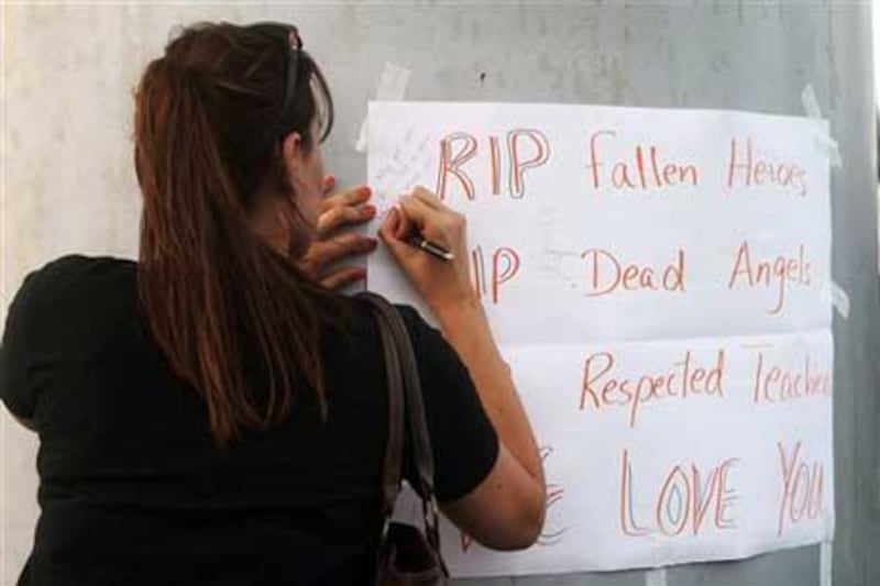 A woman writes a message during a memorial for the dead of Doha's mall fire as mourners gathered at the 'Aspire Zone' in Doha