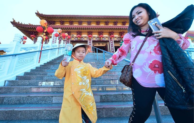 Dressed in imperial costume, Bruce Q Tran holds onto his mother Nhi's hands while they walk down steps at the Hsi Lai (Come West) Buddhist Temple in Hacienda Heights, California on the eve of the Lunar New Year. Frederic J Brown / AFP Photo