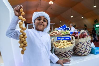 Jasim Al Qemzi, 7, poses for a souvenir photo with some Sultana dates from Zirku Island. Victor Besa / The National.