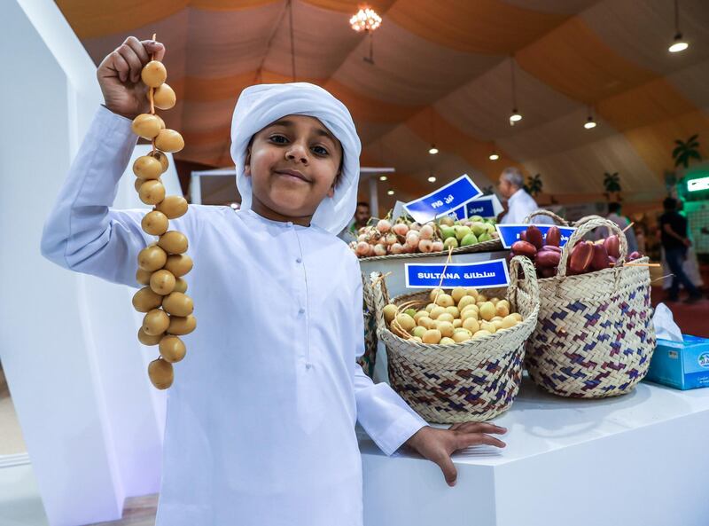 Abu Dhabi, U.A.E., July 18, 2018.  First day of the 2018 Liwa Date Festival. --  Jasim Al Qemzi (7)poses for a souvenir photo with some Sultana dates from Zirku Island.
Victor Besa / The National
Section:  NA
Reporter:  Haneen Dajani