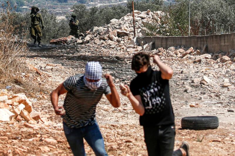 Palestinian protesters run for cover from Israeli soldiers during clashes following a weekly demonstration in the village of Kfar Qaddum in the Israeli-occupied West Bank.  AFP